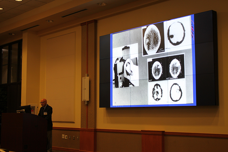 Photo of Dr. Alavi in front of a presentation of his early research