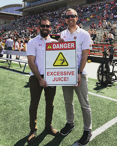 Two fellows holding a sign that says Excessive Juice