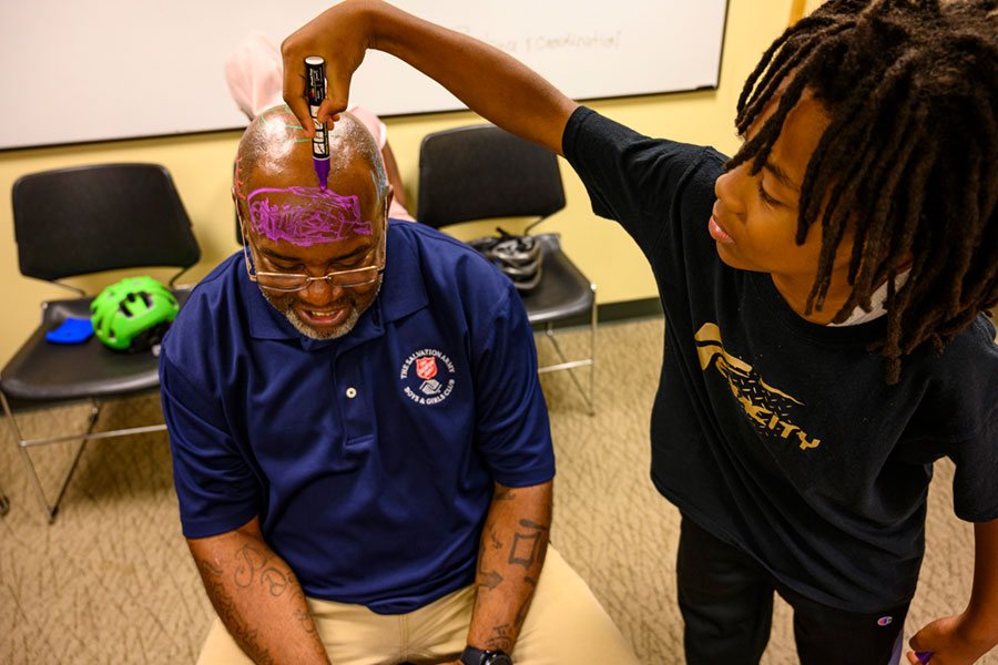 Child putting gift wrapping string on doctor's head