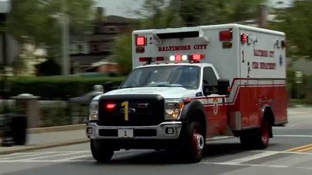 Baltimore city ambulance flashing with lights on driving through city streets