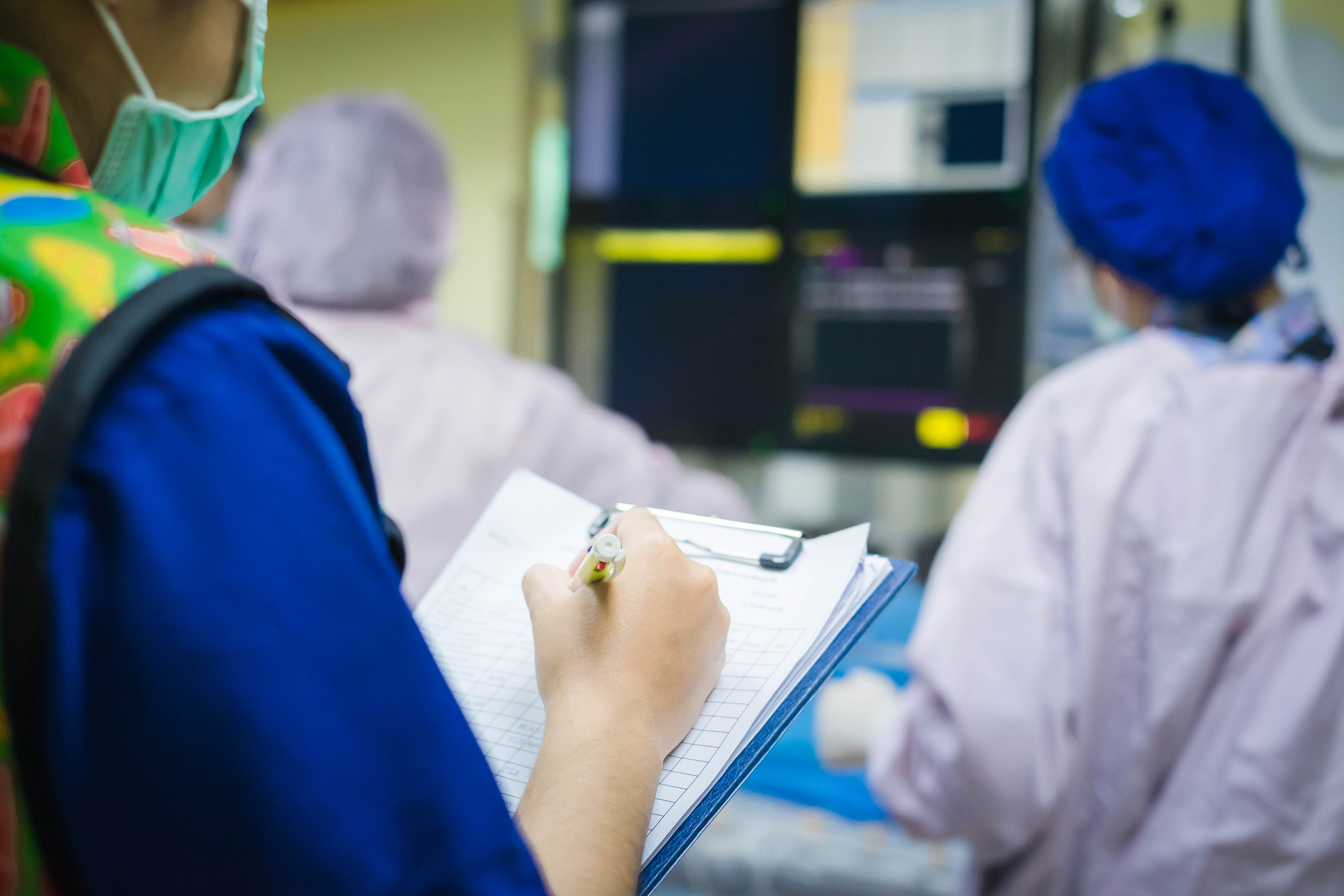 Medical professional taking notes in front of electronic charting information