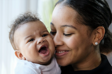A mother holds her smiling infant close to her face