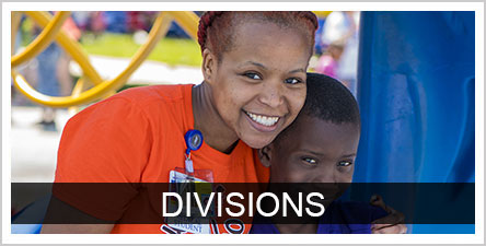 Divisions text over top background photo of UMSOM staff and a child outside smiling
