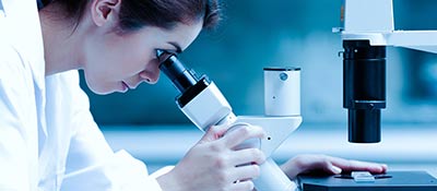 Female researcher looking into a microscope
