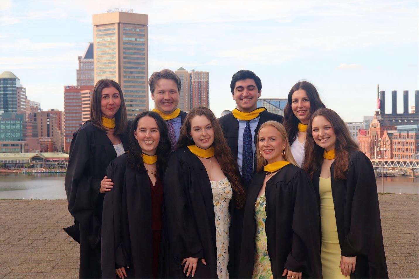 Genetic counseling class of 2025 in graduation robes in front of Baltimore skyline