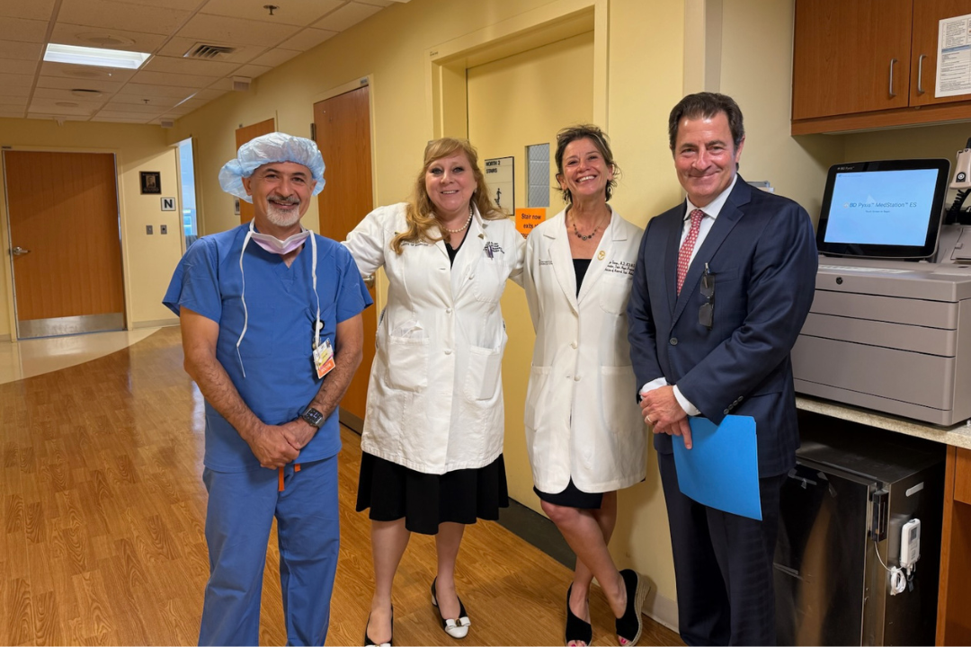 4 medical professionals in a clinical setting smiling at the camera.