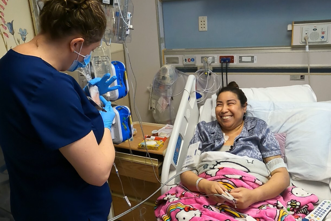 Nurse wearing gloves and mask preparing medical equipment beside Jessica Ceja lying in a hospital bed covered with a pink Hello Kitty blanket.
