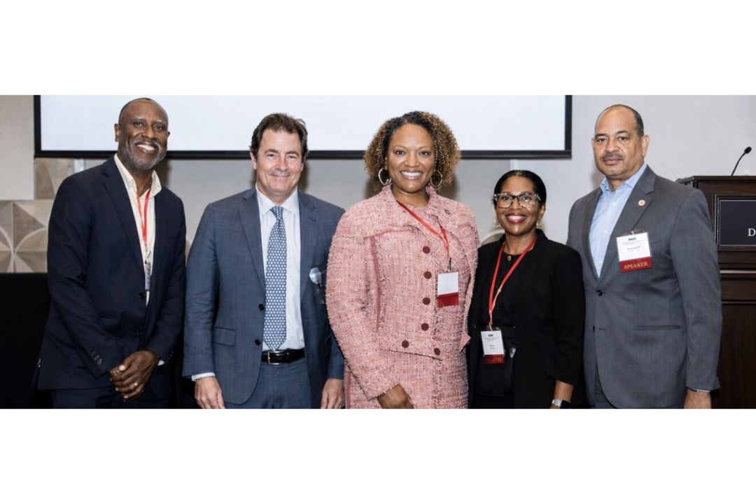 A group of business professionals at a conference smiling at the camera.