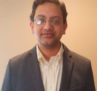 Photo of Parikshit Moitra, PhD in a grey suit jacket and white shirt against a beige background