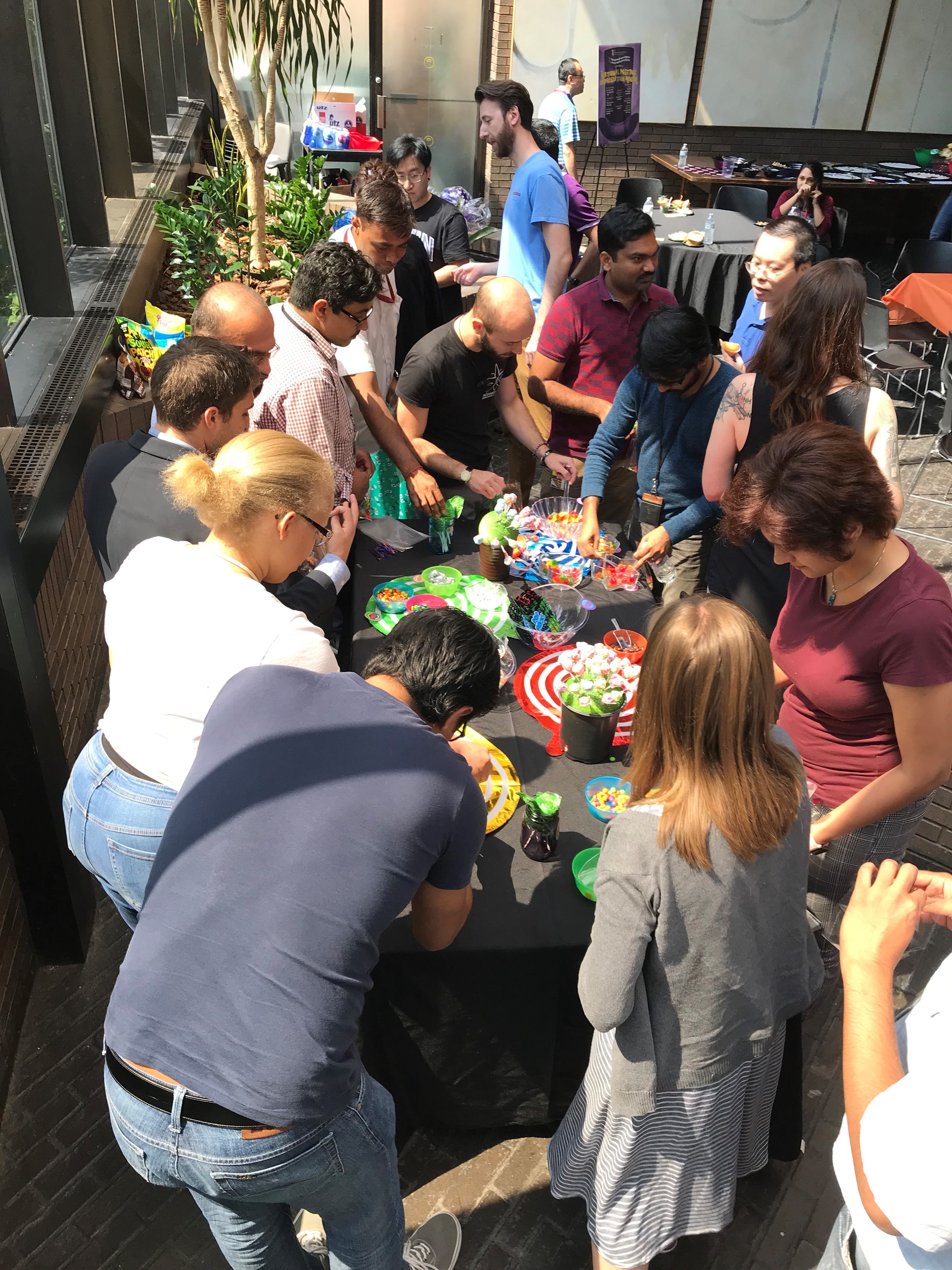 A large group of adults surrounding a table with various candies