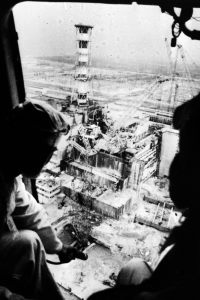 Silhouettes of two men looking down at the Chernobyl plant from a helicopter.