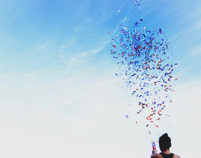Person shooting confetti into blue sky